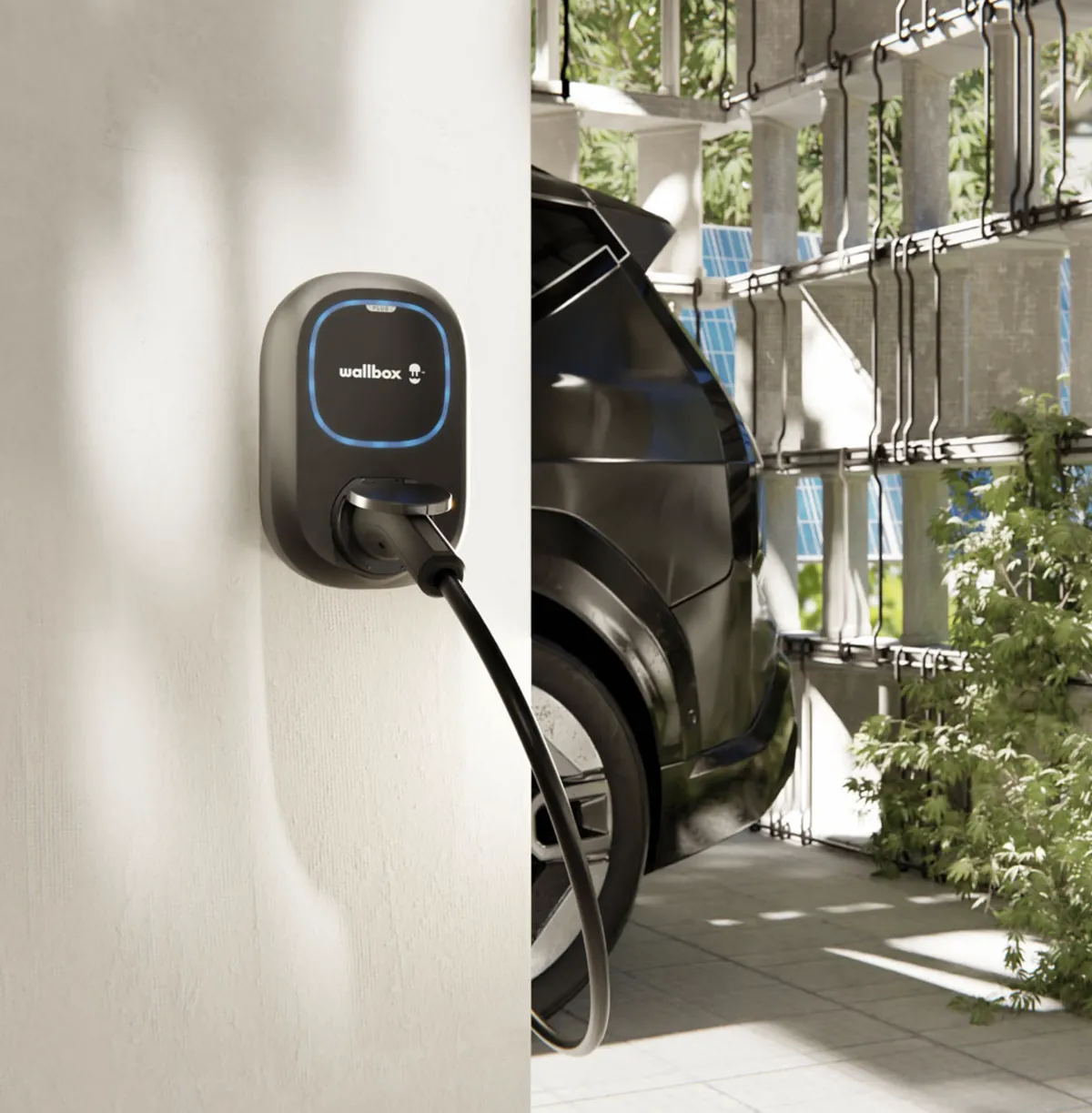 Wallbox Pulsar Plus met blauwe led aan de muur, naast een elektrische auto