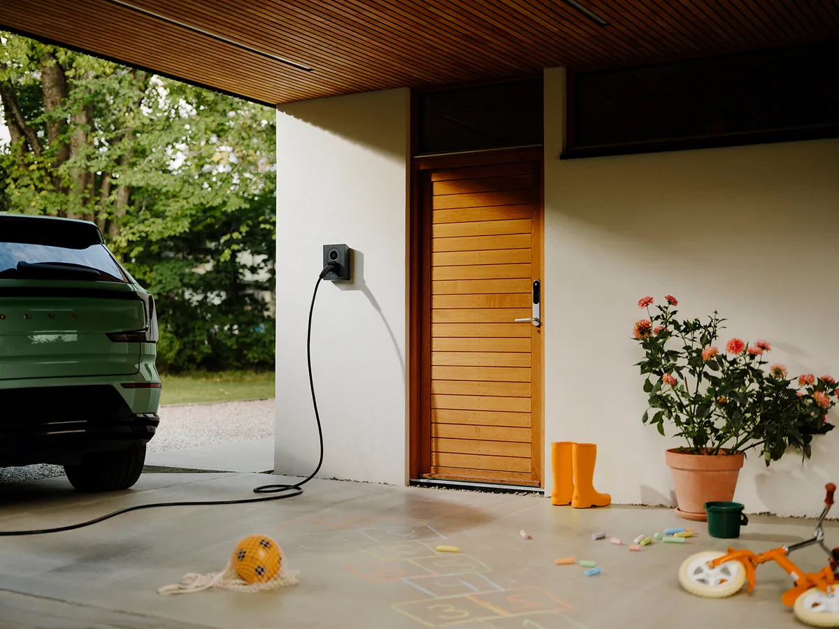 Zaptec Go 2 aan de muur van een carport, met de laadkabel in de auto