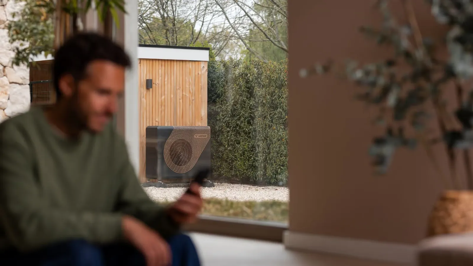 Bewoner in huis, met buiten een Weheat Sparrow warmtepomp