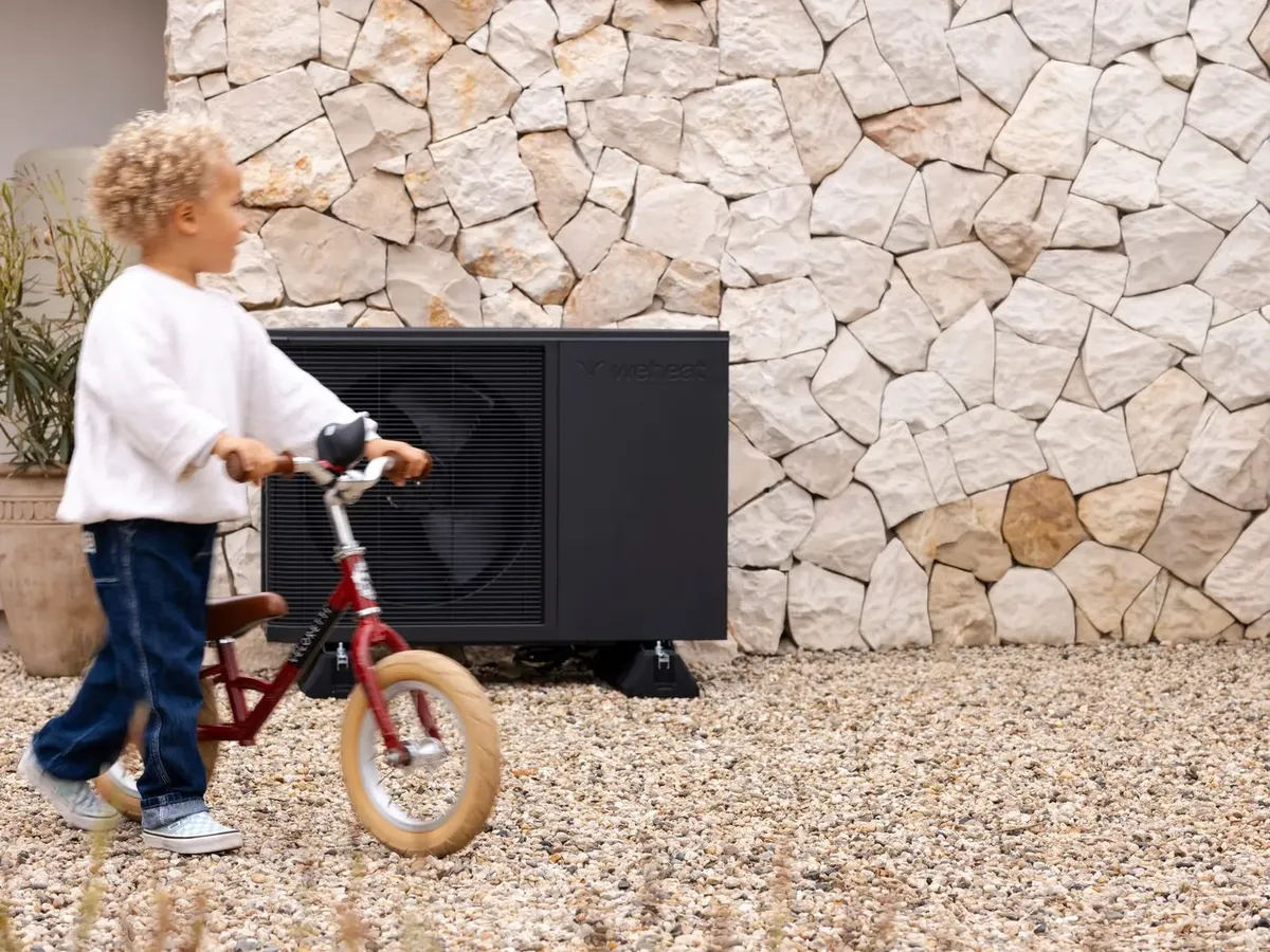 Weheat Flint warmtepomp bij een woning, met een kind op een loopfiets