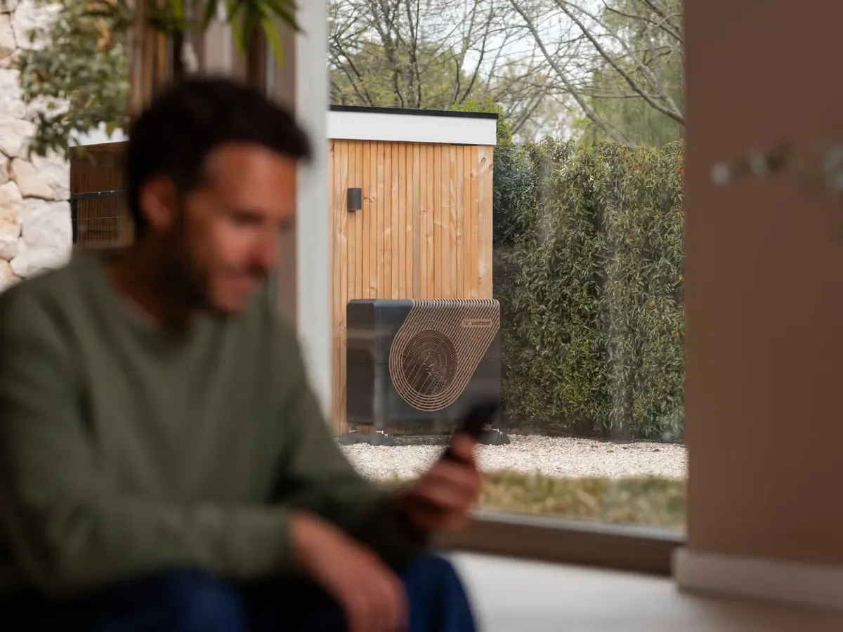 Weheat Sparrow warmtepomp buiten, gezien door het raam van een woning